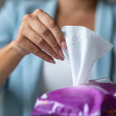 Genç kadın temizlik için antibakteriyel ıslak mendil paketini aç.