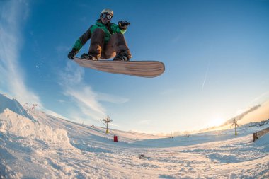 Mavi gökyüzüne atlayan snowboardcu