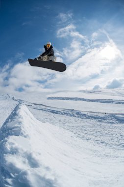 Snowboarder jumping against blue sky clipart