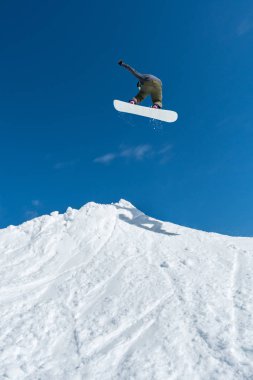 Mavi gökyüzüne atlayan snowboardcu