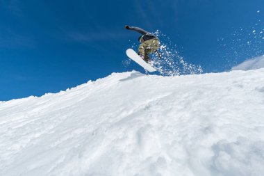 Mavi gökyüzüne atlayan snowboardcu