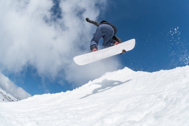 Mavi gökyüzüne atlayan snowboardcu
