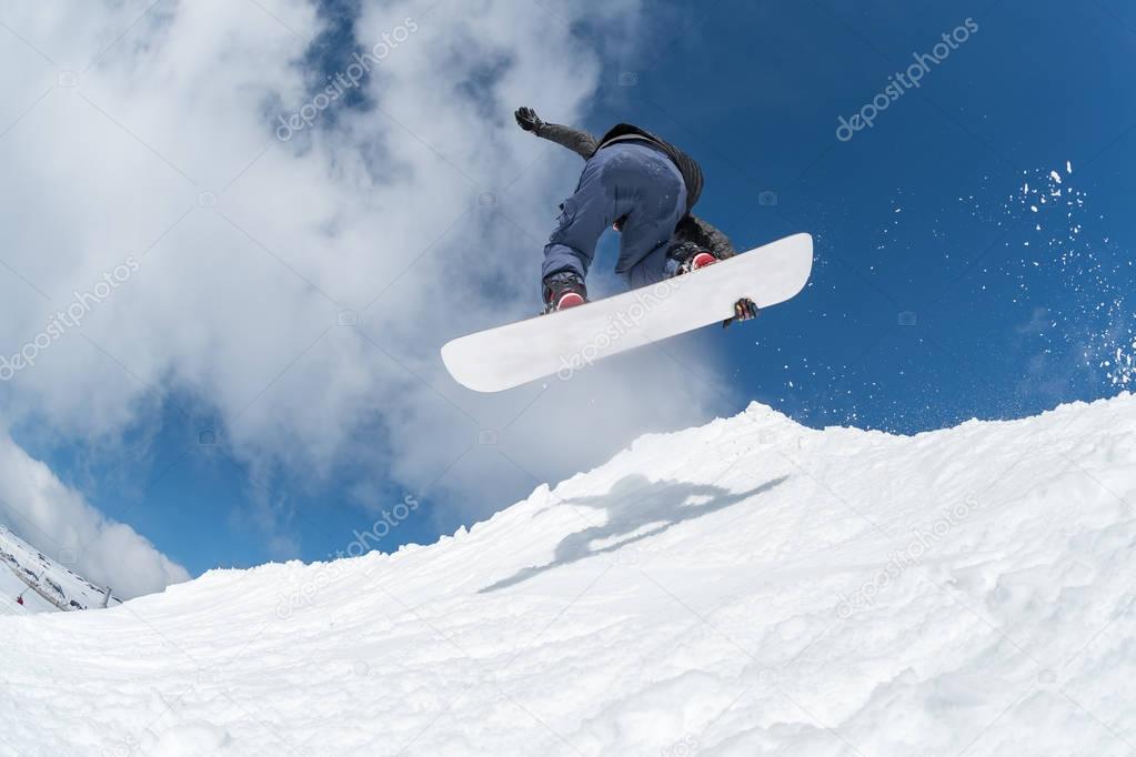 Snowboarder jumping against blue sky