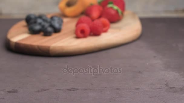 Houten bord met vers biologisch fruit en bessen — Stockvideo