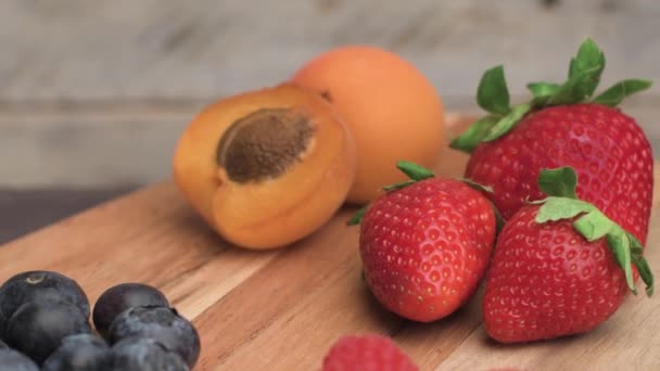 Dřevěná deska s čerstvé bio ovoce a bobule — Stock video