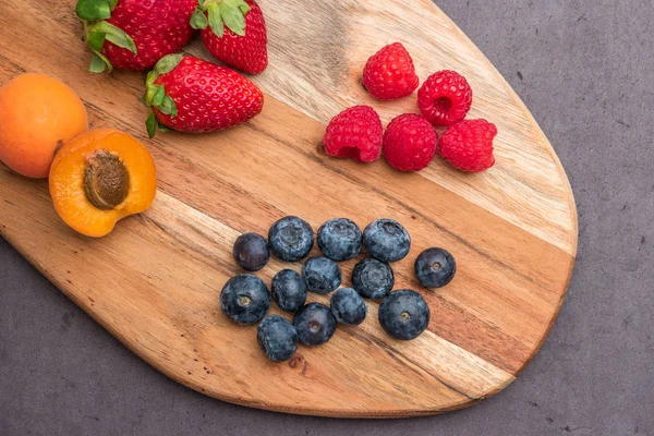 Wooden board with fresh organic fruit and berries — Stock Photo, Image
