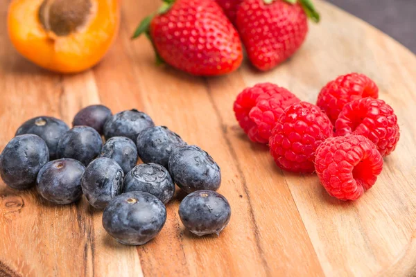 Wooden board with fresh organic fruit and berries — Stock Photo, Image