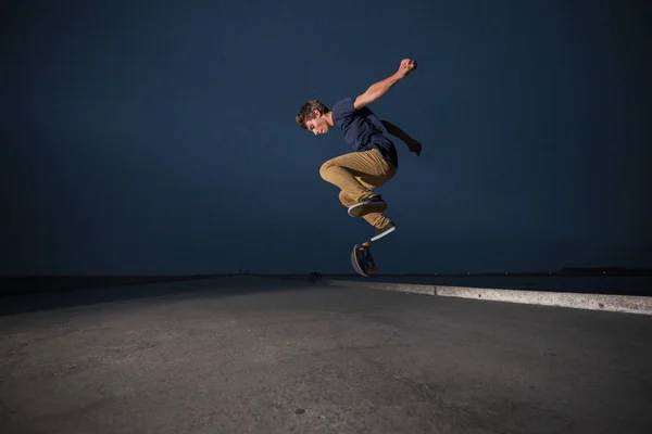 स्केटबोर्डर एक कंक्रीट फुटपाथ पर एक जैली फ्लिप प्रदर्शन कर रहा है — स्टॉक फ़ोटो, इमेज
