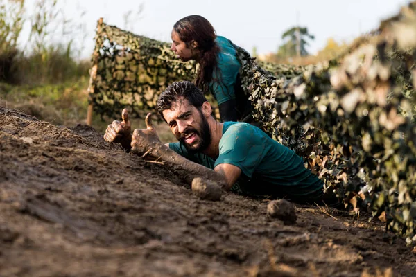 Athletes crawling through mud — Stock Photo, Image