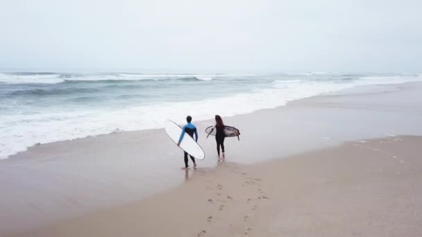 Young couple of friendly surfers entering the sea — Stock Video
