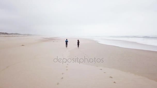 Young couple of friendly surfers running before entering the sea — Stock Video