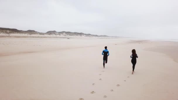 Fiatal pár fut, mielőtt a tenger barátságos szörfösök — Stock videók