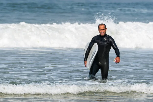 Surfer met bestuur onder zijn arm — Stockfoto