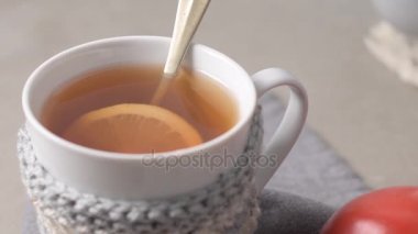 Örme sıcak kış eşarp ahşap masa üzerinde fincan limon ile çay giymiş.