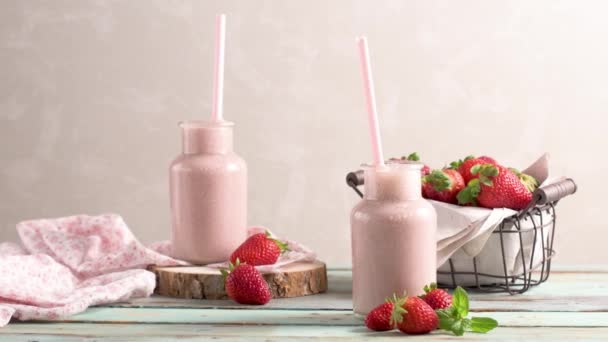 健康草莓奶昔在梅森玻璃罐子与散落的水果在一个质朴的木材背景 — 图库视频影像