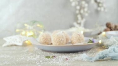 Hindistan cevizi kavrulmuş bademli ev yapımı şekerler. Işıklar ve yıldızlarla süslenmiş bir Noel masasında..