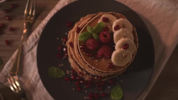 Naleśniki Malinami Plasterki Bananów Nasiona Granatów Miód Drewnianym Stole Vintage — Wideo stockowe