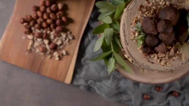テーブルの上においしい裸のコーヒーとヘーゼルナッツケーキ素朴な木のキッチンカウンタートップ — ストック動画