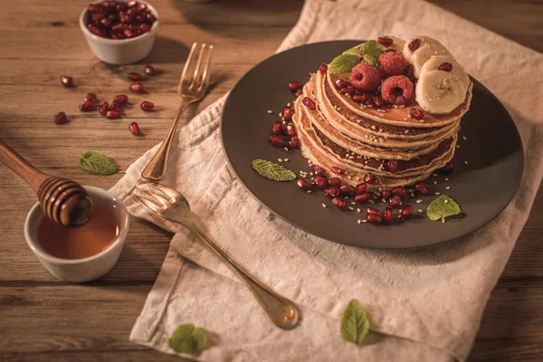 Pancakes with raspberries, banana slices, pomegranate seeds and — Stock Photo, Image