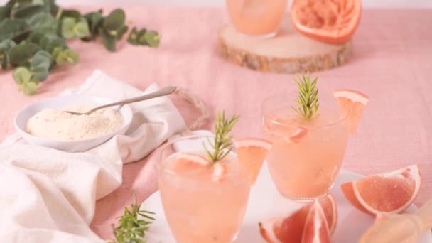 テーブルの上のガラスにローズマリーとグレープフルーツジュース 爽やかな夏のカクテル — ストック動画