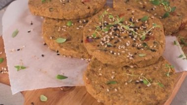 Çiğ vejetaryen burger, mercimek, kuru domates ve tahta kesme tahtasında kekik..