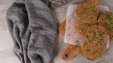 Çiğ vejetaryen burger, mercimek, kuru domates ve tahta kesme tahtasında kekik..