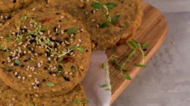 Çiğ vejetaryen burger, mercimek, kuru domates ve tahta kesme tahtasında kekik..