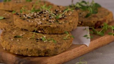 Çiğ vejetaryen burger, mercimek, kuru domates ve tahta kesme tahtasında kekik..
