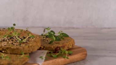 Çiğ vejetaryen burger, mercimek, kuru domates ve tahta kesme tahtasında kekik..