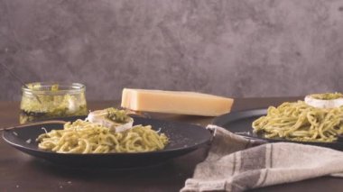 Karanlık mutfak tezgahında fesleğen soslu ve peynirli taze spagetti..