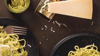 Karanlık mutfak tezgahında fesleğen soslu ve peynirli taze spagetti..