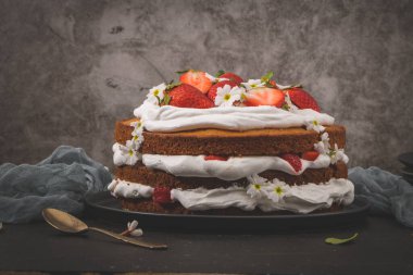 Çilekli pasta, çilekli kek taze çilek ve koyu mutfak tezgahında ekşi krema..