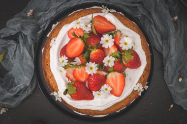 Çilekli pasta, çilekli kek taze çilek ve koyu mutfak tezgahında ekşi krema..