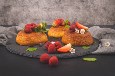 Yuvarlak tahtada karamel kremalı puding ve koyu mutfak tezgahı..