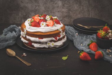 Çilekli pasta, çilekli kek taze çilek ve koyu mutfak tezgahında ekşi krema..