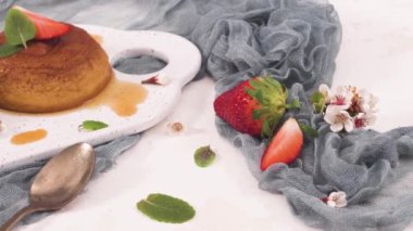 Beyaz seramik tepside ve mutfak tezgahında karamel kremalı puding..