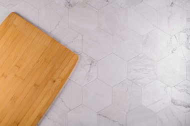Modern altıgen desenli mermer taş tezgahın ahşap kesim tahtasının üst görüntüsü.