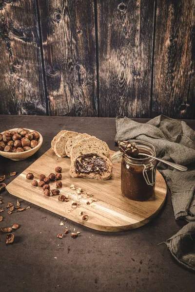 Vegan chocolate spread made of organic almond butter and organic cacao and honey, on dark rustic kitchen counter top.