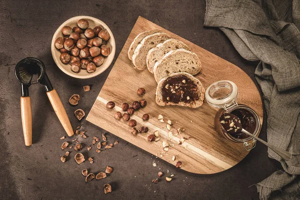 Vegan chocolate spread made of organic almond butter and organic cacao and honey, on dark rustic kitchen counter top.