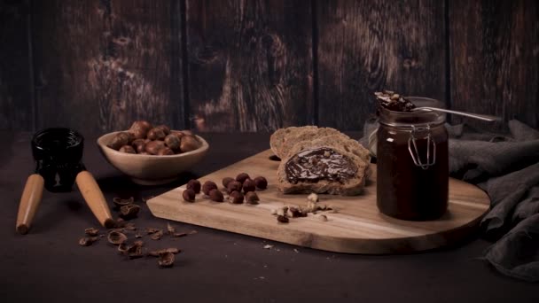 有機アーモンドバターと有機カカオと蜂蜜で作られたビーガンチョコレートスプレッド 暗い素朴なキッチンカウンターの上に — ストック動画