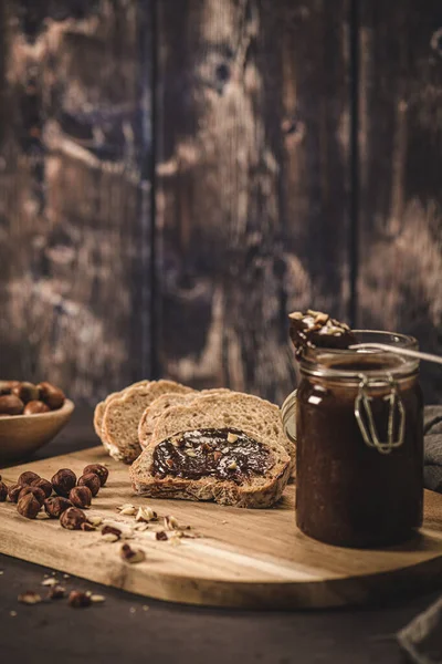 Vegan chocolate spread made of organic almond butter and organic cacao and honey, on dark rustic kitchen counter top.