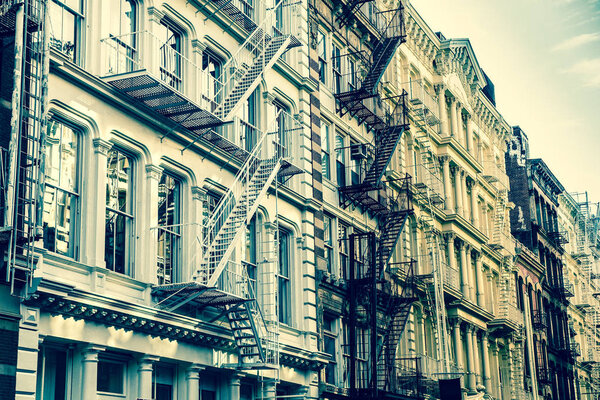 New York City view of exterior facade on ornate old apartment building residence with fire escapes seen from lower Manhattan with vintage retro filter effect.