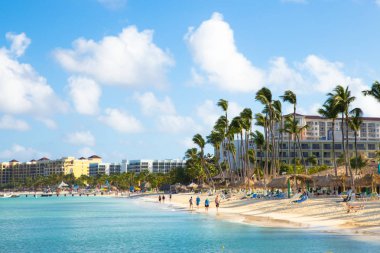Noord, Aruba - 14 Şubat 2017: Güzel manzaralı turist alan inpalm Beach Aruba boyunca palmiye ağaçları, ziyaretçiler ve kum