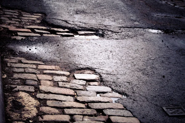 Old New York City cobblestone street repaired with asphalt