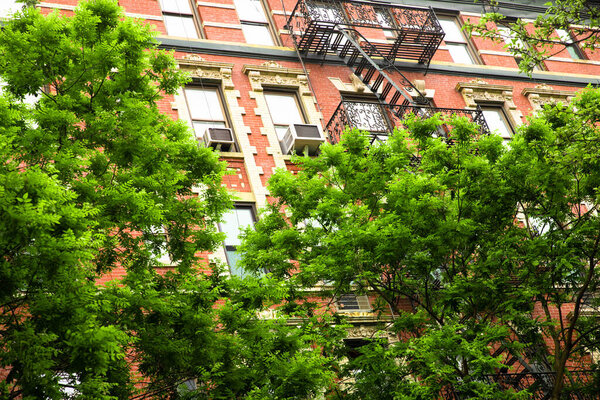 New York City brick apartment building in spring surrounded by green trees.