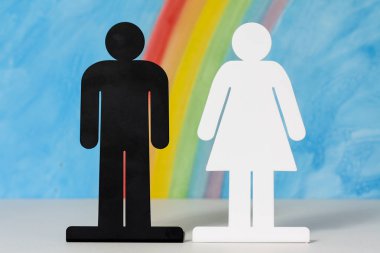 Man and women icons with a rainbow and blue sky clipart
