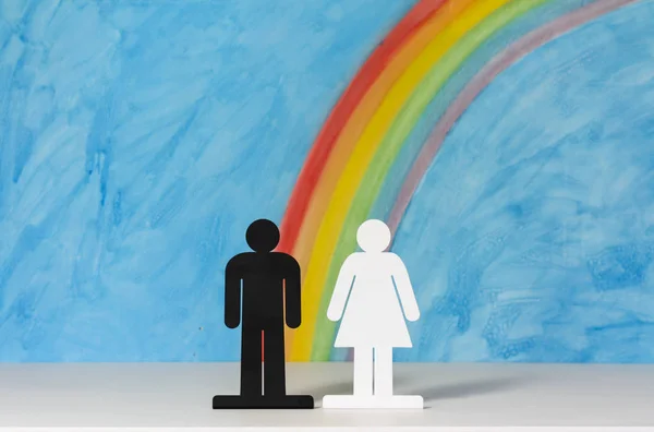 Ícones de homem e mulher com um arco-íris e céu azul — Fotografia de Stock
