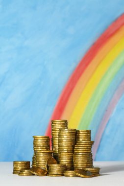 Gold Australian dollar coins against a blue sky and rainbow back clipart