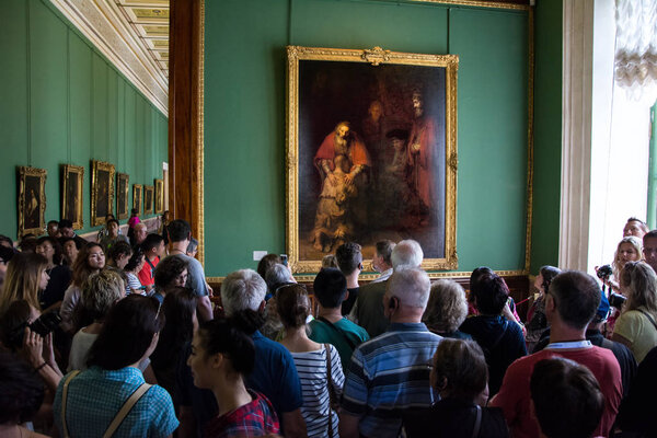 Visitors admire paintings by Rembrandt, "The Return of the Prodi