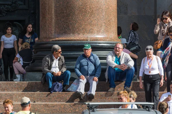 Tourists rest in the shadow of the majestic columns of St. Isaac — Stock Photo, Image